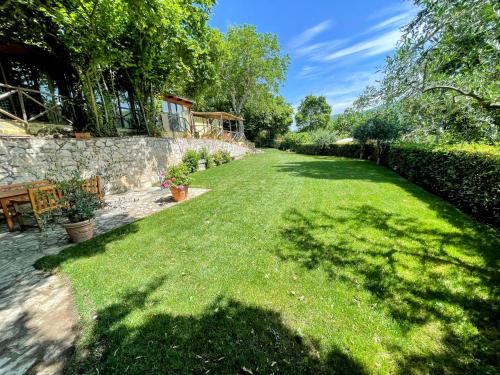 a yard with a stone wall and green grass at Torretta sleeps 5 with pool and exclusive gardens plus private verandah in Strettura