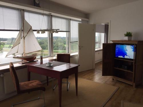 a living room with a table and a sailboat in the window at Ferienwohnung-Seemoewe in Schleswig