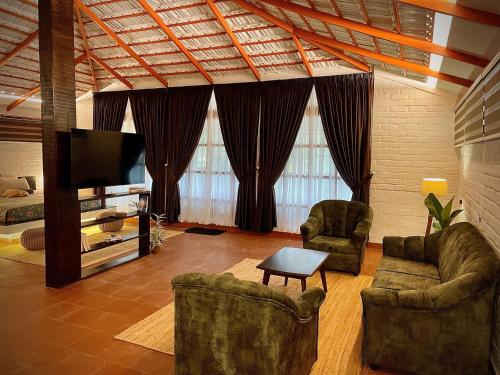 瓦卡拉的住宿－Boho's Hotel，客厅配有2把椅子和平面电视