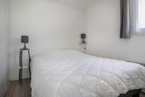 a white bed in a white bedroom with a window at Maison avec piscine à 200m de la plage in Saint-Michel-Chef-Chef