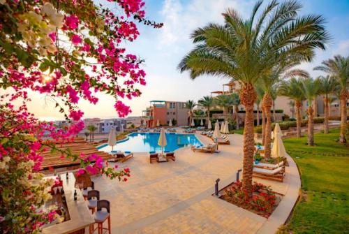 een resort met een zwembad en palmbomen en roze bloemen bij Luxury suite for rent in Sahl Hasheesh in Hurghada