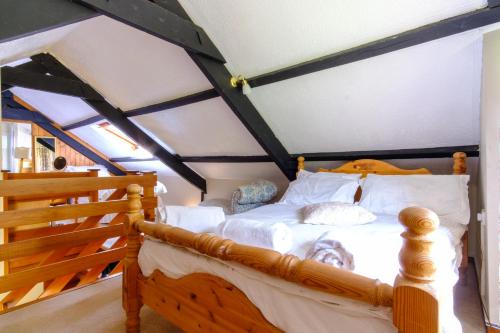 une chambre avec un lit en bois avec des draps blancs dans l'établissement Lakeside Cottage, à Carmarthen