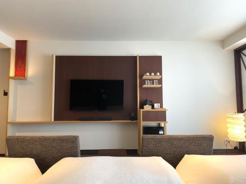 a hotel room with a flat screen tv on the wall at HOTEL AMANEK Kanazawa in Kanazawa