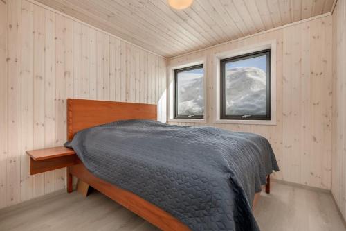 a bedroom with a bed and two windows at Hodlekvevegen 308 - Flott hytte midt i skisenteret in Sogndal