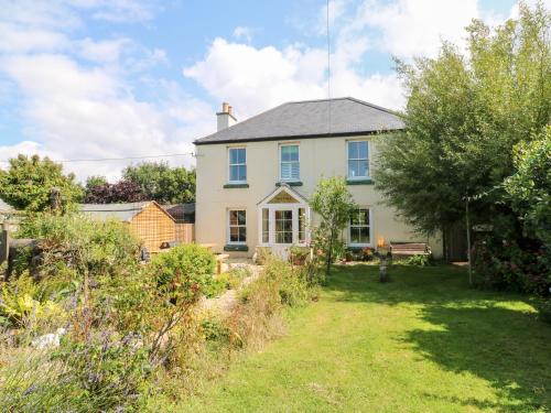 a white house with a garden in front of it at Pentira in Helston