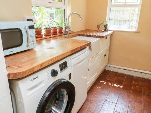 a kitchen with a washer and dryer under a counter at Pentira in Helston