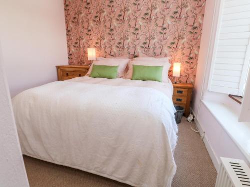 a bedroom with a white bed with a floral wallpaper at Pentira in Helston