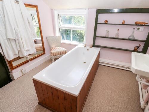 a bathroom with a tub and a sink and a mirror at Pentira in Helston