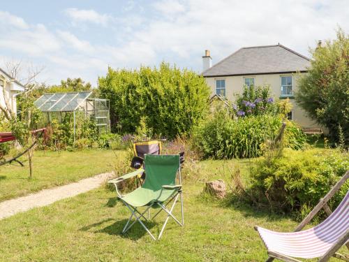 a yard with two lawn chairs and a house at Pentira in Helston