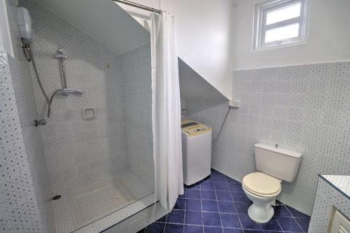 a white bathroom with a shower and a toilet at Turquoise in Blue Bay