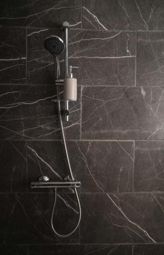 a shower in a bathroom with a stone wall at Eia Street Apartments Belfast in Belfast