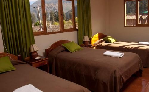 ウルバンバにあるPosada Las Tres Mariasのベッド2台、緑のカーテン、窓が備わる客室です。