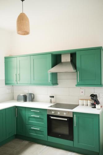 a green kitchen with white counters and green cabinets at Eia Street Apartments Belfast in Belfast