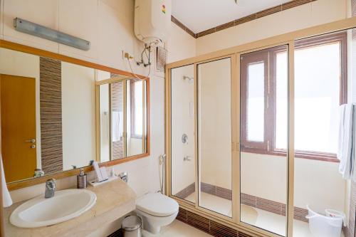 a bathroom with a sink and a toilet and a mirror at Ahuja Residency Cyber City I in Gurgaon