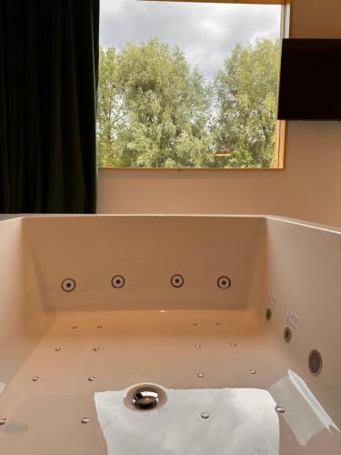 La salle de bains est pourvue d'une baignoire et d'une fenêtre. dans l'établissement Quinze suites et wellness de luxe, à Ciney