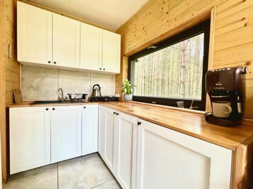 eine Küche mit weißen Schränken und einem großen Fenster in der Unterkunft Leśny Azyl in Kępiaste