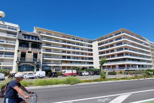 een man die op een fiets door een straat met een gebouw fietst bij Océan bleu - Studio bord de plage in La Baule