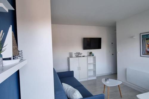 een woonkamer met een blauwe bank en een tafel bij Océan bleu - Studio bord de plage in La Baule