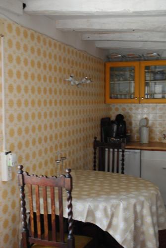 une chambre avec une table et une cuisine avec du papier peint jaune dans l'établissement Mays' House, à Availles-Limouzine