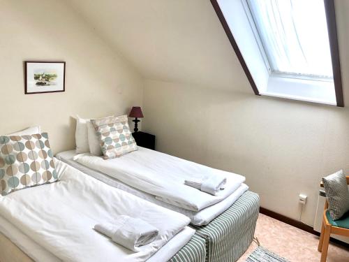 um quarto com uma cama com lençóis brancos e uma janela em Gåsen Out em Burgsvik