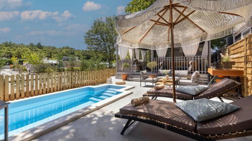 a patio with a pool and chairs and an umbrella at Polidor Camping Resort in Poreč