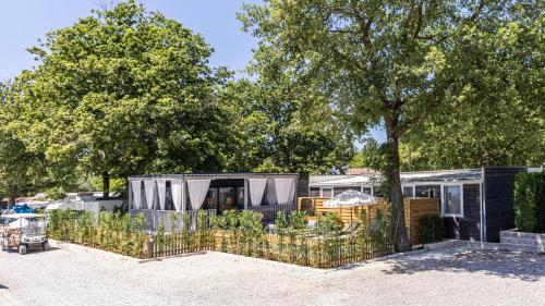 a small black house with a fence and trees at Polidor Camping Resort in Poreč