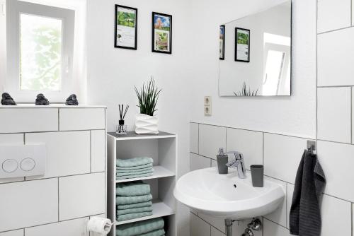 ein weißes Badezimmer mit einem Waschbecken und einem Spiegel in der Unterkunft Ferienwohnung Auszeit in Salem
