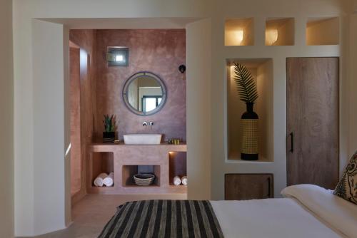 a bathroom with a bed and a sink and a mirror at Aeon Suites - Adults Only in Pirgos