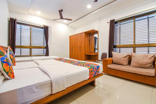 a bedroom with a bed and a couch and windows at FabHotel The Address in Nashik