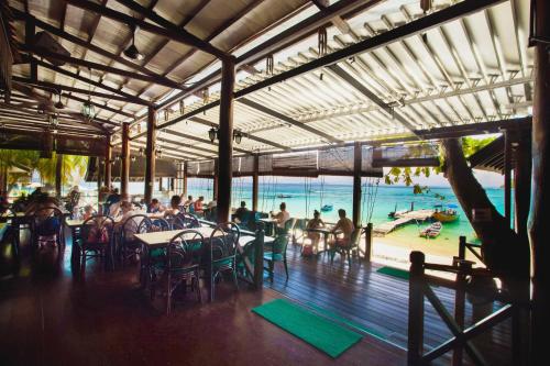 a patio area with tables and chairs and umbrellas at Tuna Bay Island Resort in Perhentian Islands