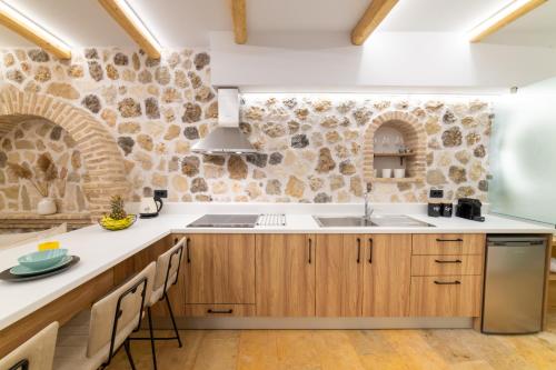 una cocina con armarios de madera y una pared de piedra. en Domus Inn Luxury Apartments, en Parga