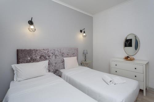 2 camas blancas en una habitación con espejo en BeGuest Gandarinha Apartment, en Cascais