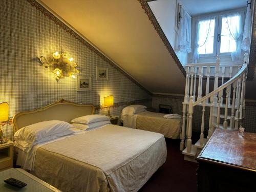 a bedroom with two beds and a staircase at Hotel & SPA Duchessa Isabella Collection by GSA Hotels in Ferrara