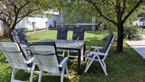 a table and four chairs around a table and a tree at Apartment and rooms Corina in Bilje