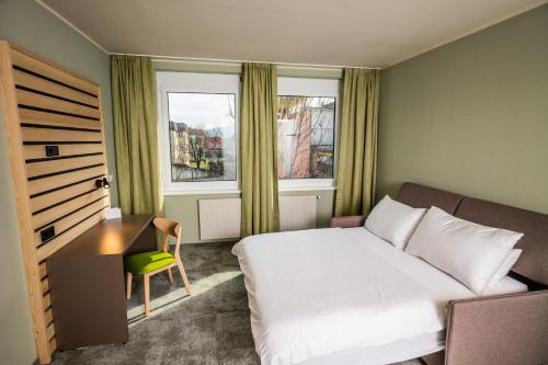 a bedroom with a bed and a desk and a window at flexymotel Spielberg in Spielberg