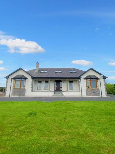 a large white house with a green lawn at Tour House, A Country Escape set in Natures Beauty in Youghal
