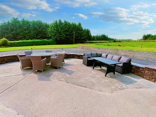 a patio with a table and chairs and a couch at Tour House, A Country Escape set in Natures Beauty in Youghal