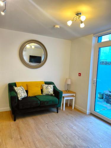 a living room with a green couch and a mirror at Bangor Central Apartments in Bangor