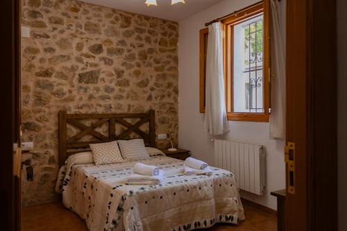 AndillaにあるCasa rural La Murallaのベッドと石の壁のある寝室