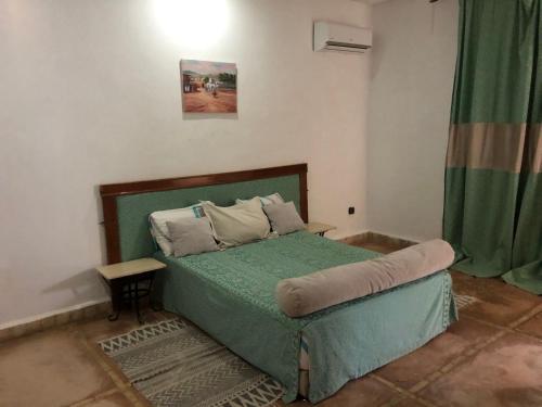 een slaapkamer met een bed met een groen dekbed bij Villa Moulay Faycal in Marrakesh