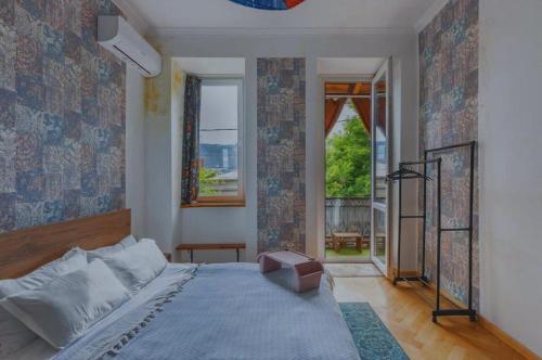 a bedroom with a bed and a large window at kushki's home in Tbilisi City