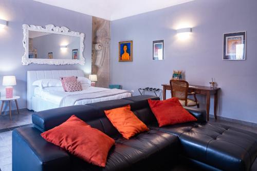 a living room with a black leather couch with orange pillows at Palazzo Gilistro in Siracusa