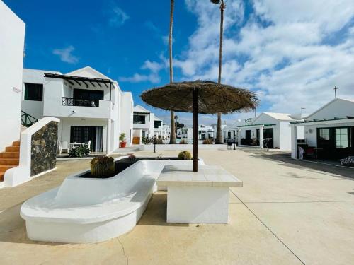 a bench with an umbrella in front of a building at Casa Adelfa in Puerto del Carmen
