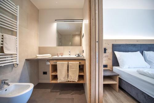 a small bathroom with a sink and a bed at Apartments Chalet Silva in Selva di Val Gardena