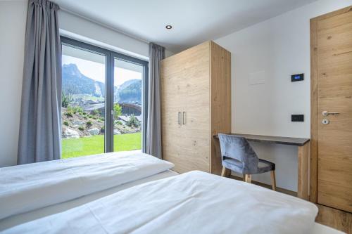 a bedroom with a bed and a desk and a window at Apartments Chalet Silva in Selva di Val Gardena