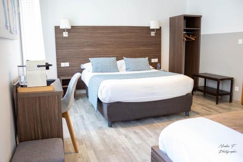 a bedroom with two beds and a wooden headboard at Hotel de la Cathedrale in Beauvais