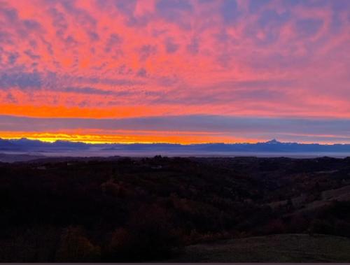 a sunset over a field with trees and clouds at Peter Pan in Castellino Tanaro