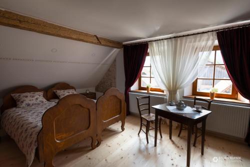 Begunje pri CerkniciにあるNotranjska hiša - traditional country house, close to the world attraction Cerknica lakeのベッドルーム1室(ベッド1台、テーブル、窓2つ付)