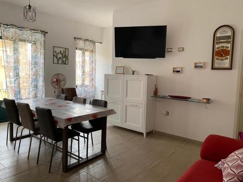 ein Esszimmer mit einem Tisch, Stühlen und einem TV in der Unterkunft La casa sotto il Fortino in SantʼAntìoco