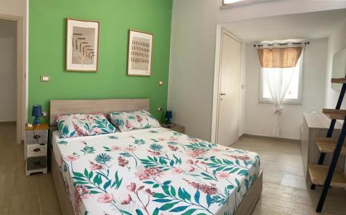 a bedroom with a bed and a green wall at La casa sotto il Fortino in SantʼAntìoco